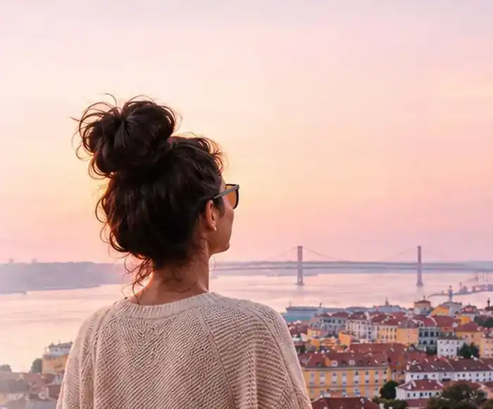 A woman looking out over Lisbon and the Tagus river at sunset